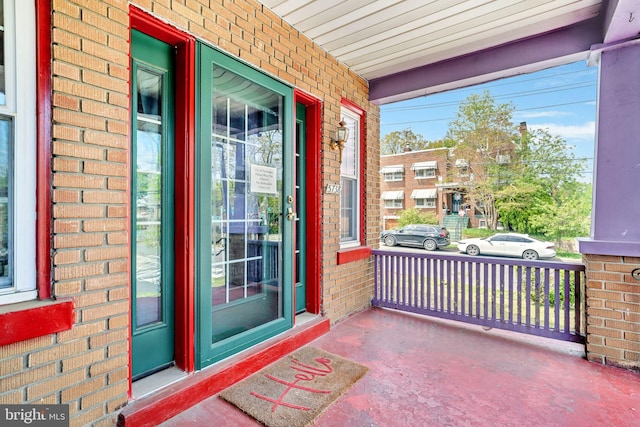 doorway to property with brick siding and covered porch