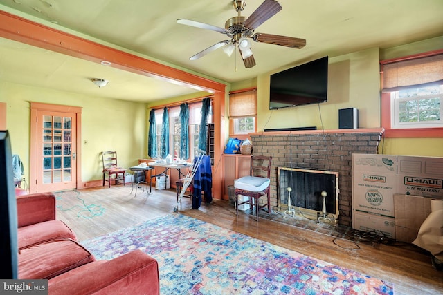 living area featuring a fireplace, wood finished floors, and ceiling fan