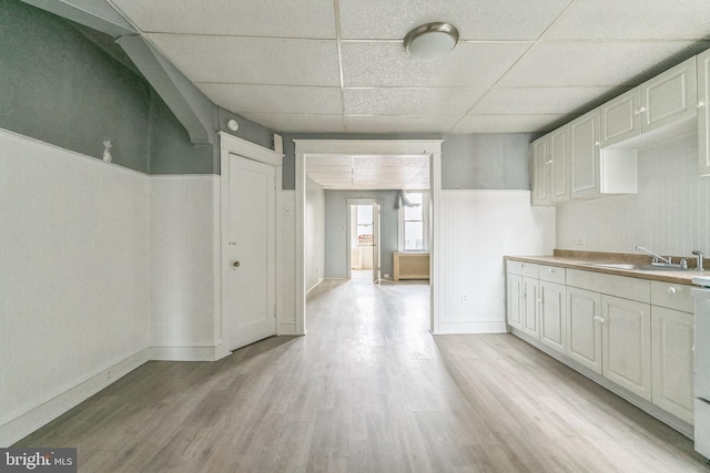 3905 L St, Philadelphia, PA 19124 - kitchen featuring a paneled ceiling, light wood-style flooring, white cabinetry, wainscoting, and a sink