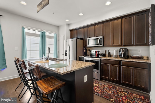 7204 Wood Trail Dr, Lanham, MD 20706 - kitchen with a kitchen breakfast bar, an island with sink, dark brown cabinets, appliances with stainless steel finishes, and a sink
