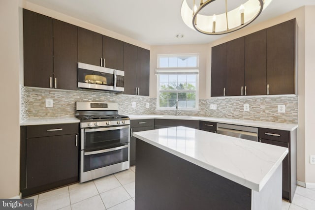 kitchen featuring a sink, light tile patterned flooring, a kitchen island, tasteful backsplash, and appliances with stainless steel finishes