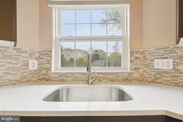kitchen with a wealth of natural light, decorative backsplash, and a sink