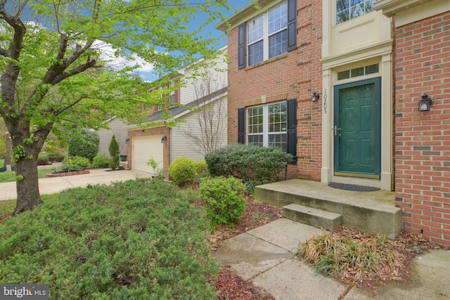 property entrance with brick siding, driveway, and a garage