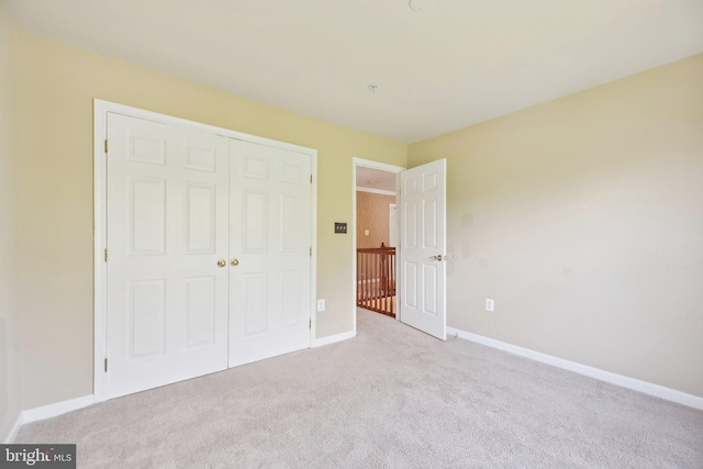 unfurnished bedroom featuring baseboards, carpet flooring, and a closet