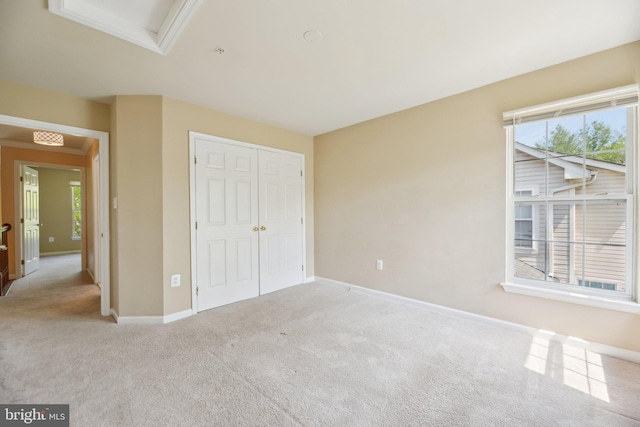 unfurnished bedroom with attic access, carpet floors, a closet, and multiple windows
