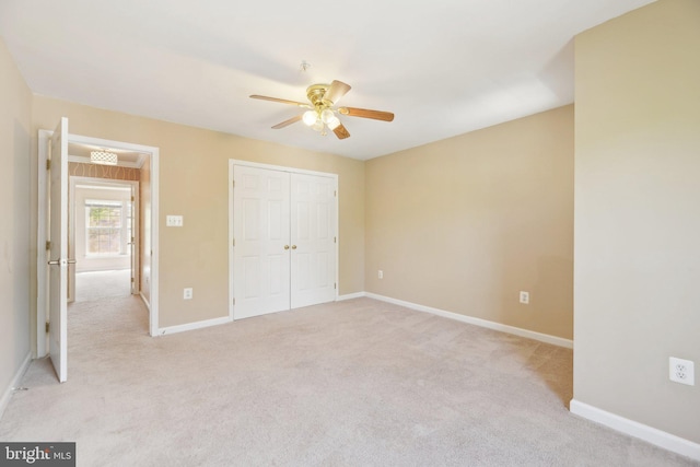unfurnished bedroom with baseboards, light carpet, ceiling fan, and a closet