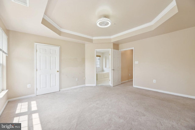 unfurnished bedroom featuring a raised ceiling, baseboards, light colored carpet, and ornamental molding