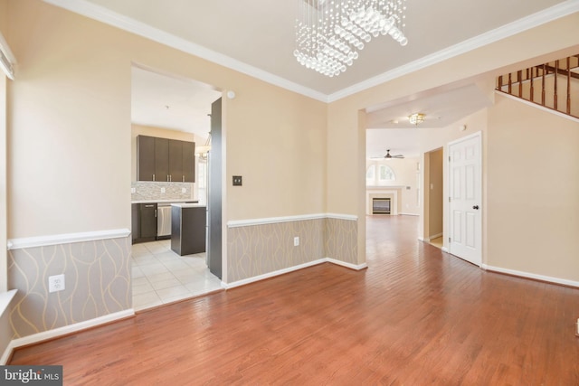 spare room featuring light wood finished floors, baseboards, and crown molding