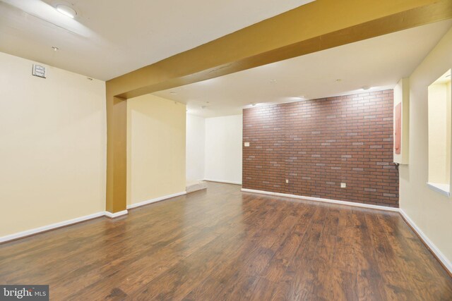 interior space with brick wall, baseboards, and wood finished floors