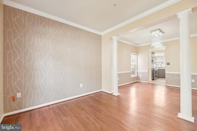 spare room featuring wainscoting, wood finished floors, and decorative columns