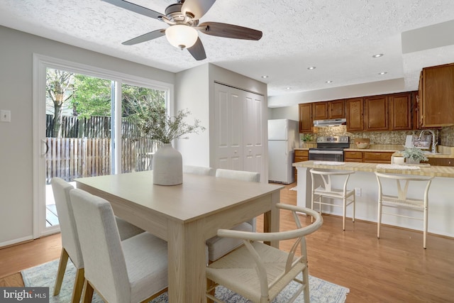 dining area with ceiling fan, a textured ceiling, recessed lighting, baseboards, and light wood-type flooring