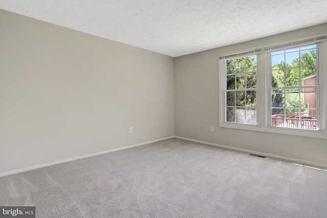 carpeted spare room featuring baseboards, a textured ceiling, and visible vents