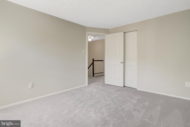 unfurnished bedroom featuring baseboards, carpet, and a closet