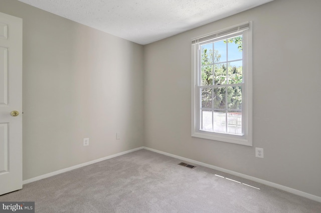 carpeted spare room featuring baseboards, a textured ceiling, and visible vents