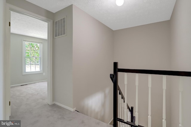 staircase with baseboards, carpet, a textured ceiling, and visible vents