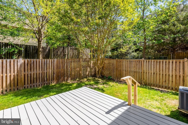 wooden terrace with a fenced backyard, central AC unit, and a lawn