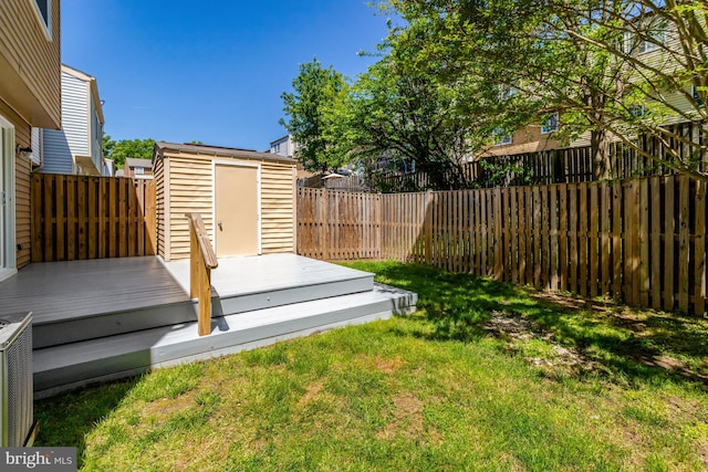 view of yard with a storage shed, a deck, an outdoor structure, and a fenced backyard