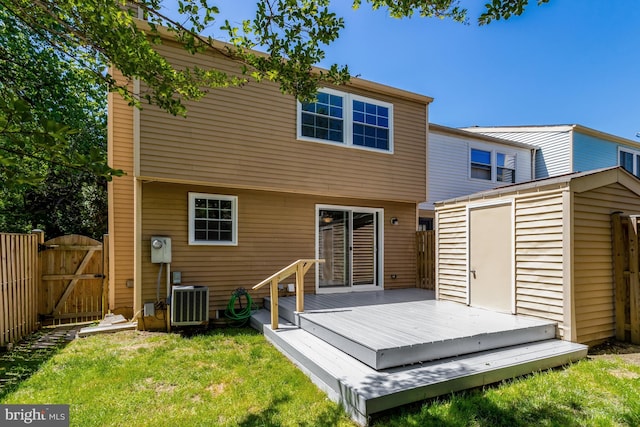 back of house with an outdoor structure, a wooden deck, a shed, a gate, and a yard