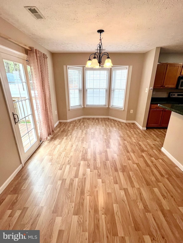 unfurnished dining area featuring light wood-style floors and a textured ceiling