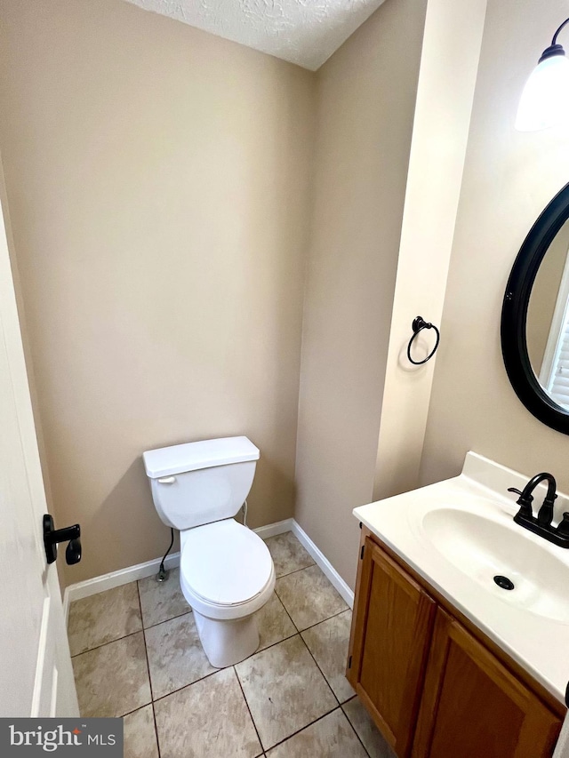 bathroom with toilet, vanity, baseboards, and a textured ceiling