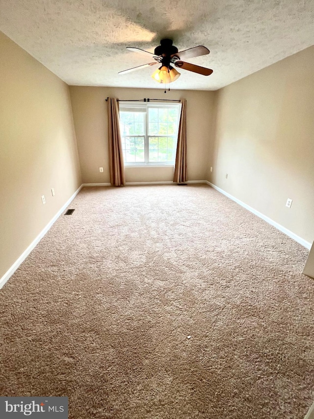 empty room featuring visible vents, baseboards, a ceiling fan, and a textured ceiling