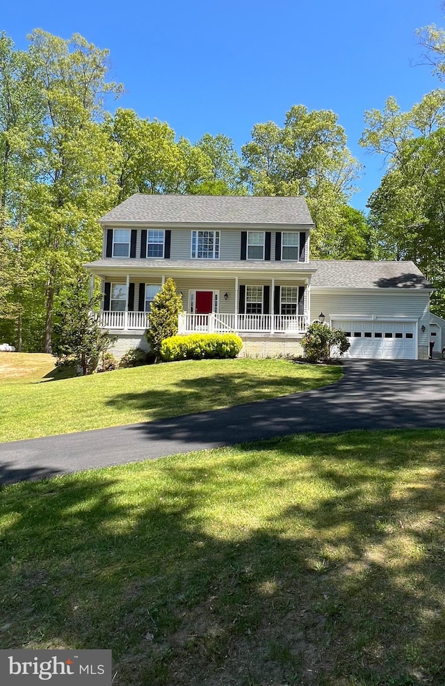 colonial house featuring driveway, a porch, a front lawn, and a garage