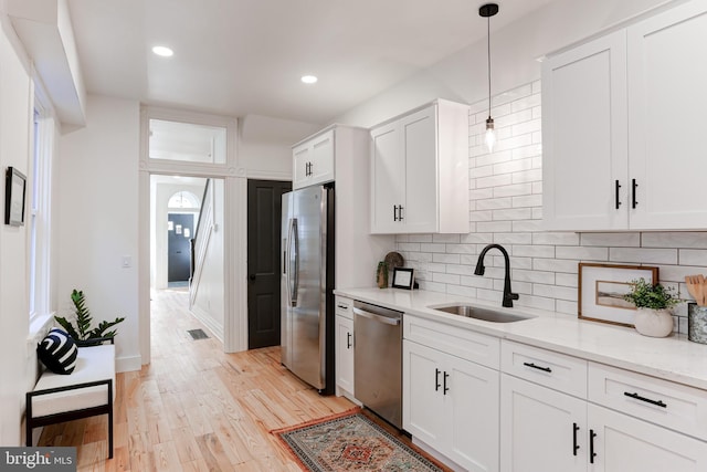 kitchen with white cabinets, stainless steel appliances, a sink, visible vents, and backsplash