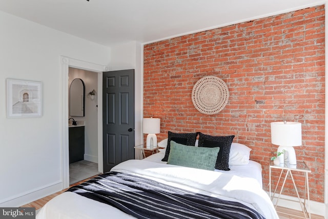 bedroom featuring light wood finished floors, brick wall, and baseboards