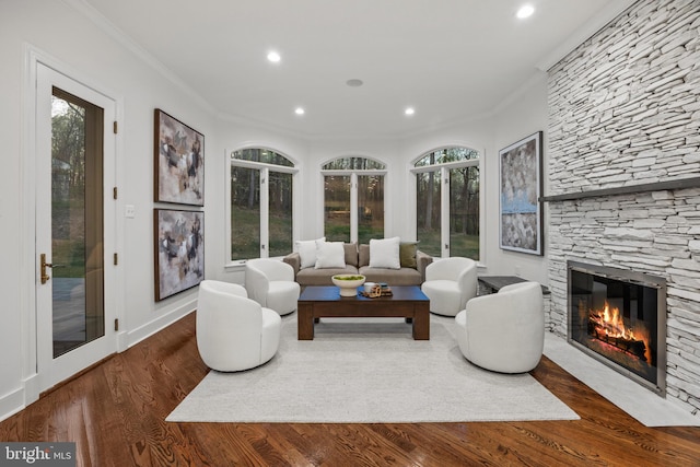 living area featuring recessed lighting, a stone fireplace, wood finished floors, and ornamental molding