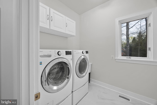 washroom featuring marble finish floor, washer and clothes dryer, visible vents, baseboards, and cabinet space