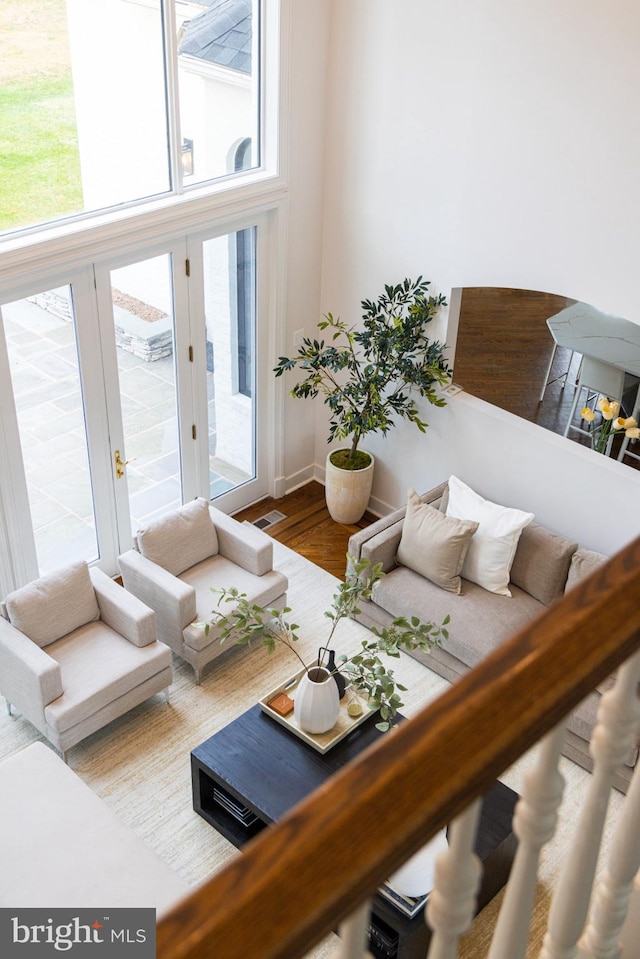 living room featuring wood finished floors, visible vents, baseboards, and a high ceiling