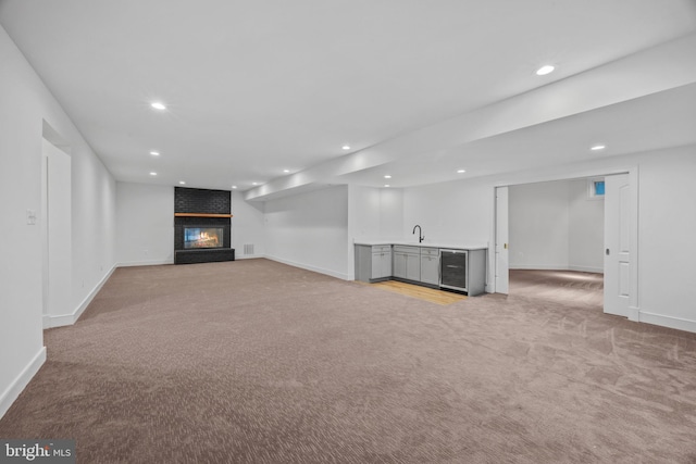 finished below grade area with light carpet, baseboards, recessed lighting, indoor wet bar, and beverage cooler