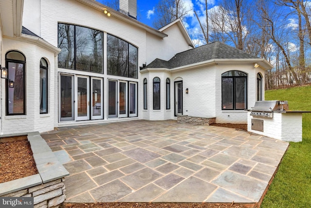 rear view of house featuring exterior kitchen, a patio area, brick siding, and a chimney