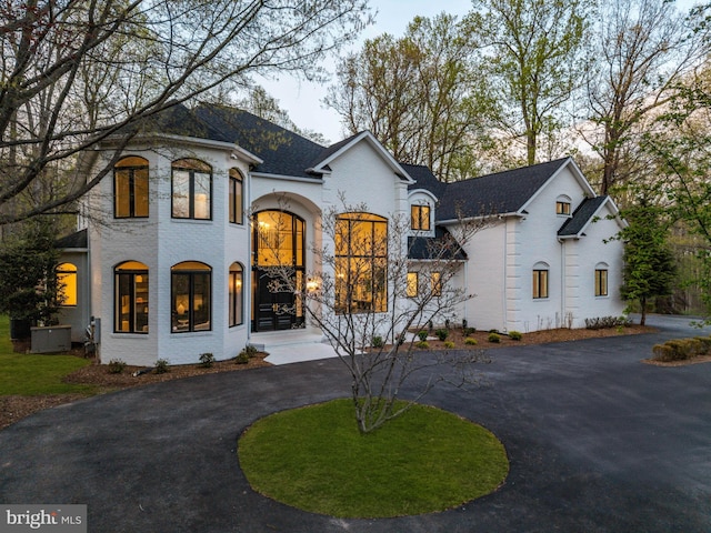 french provincial home featuring brick siding and curved driveway