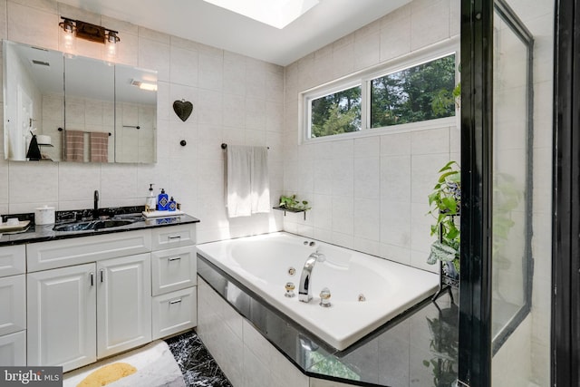 4705 Exeter St, Annandale, VA 22003 - bathroom with tile walls, vanity, a tub with jets, a skylight, and marble finish floors