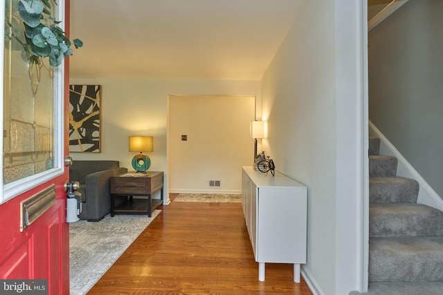 foyer entrance featuring stairway, visible vents, and wood finished floors