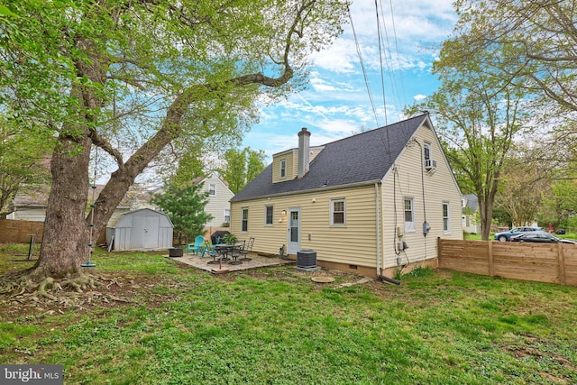 back of house featuring an outbuilding, a storage unit, a patio area, fence, and a chimney