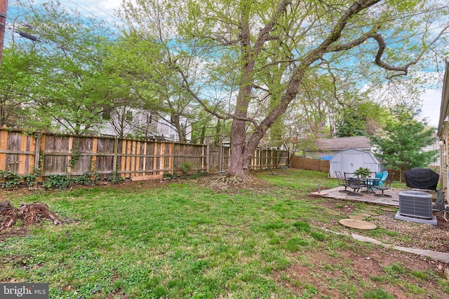 view of yard featuring central air condition unit, a fenced backyard, a storage shed, and an outbuilding