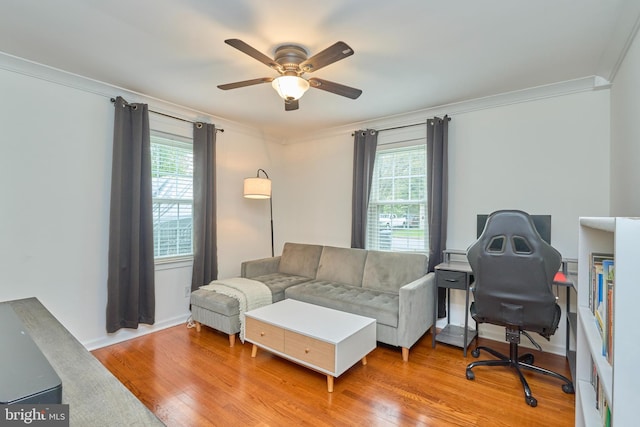 living area with wood finished floors, a ceiling fan, ornamental molding, and a healthy amount of sunlight