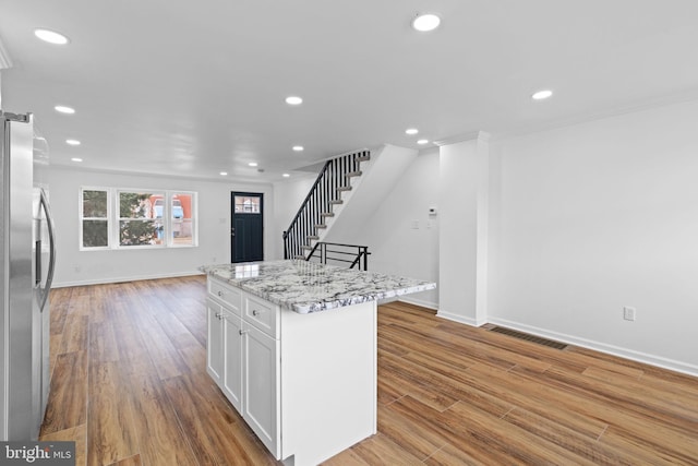 kitchen featuring stainless steel fridge with ice dispenser, visible vents, white cabinetry, and wood finished floors