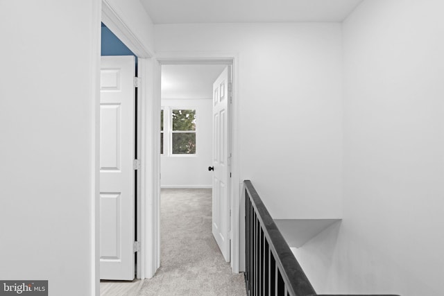 corridor with baseboards, an upstairs landing, and light colored carpet
