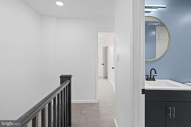 hall featuring recessed lighting, carpet flooring, a sink, an upstairs landing, and baseboards