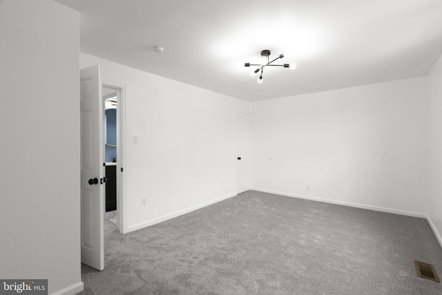 spare room with carpet flooring, baseboards, and visible vents