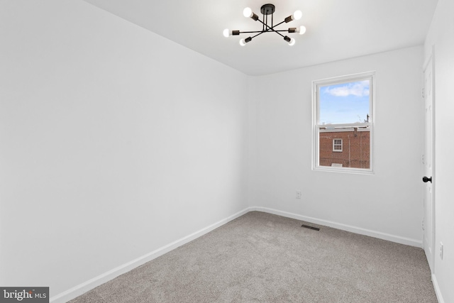 carpeted empty room with visible vents, baseboards, and a notable chandelier