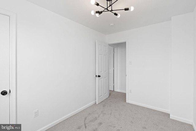 unfurnished bedroom with carpet floors, baseboards, and a chandelier