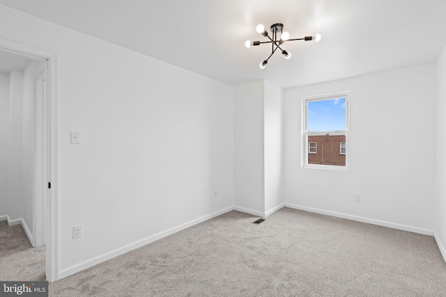 spare room featuring carpet floors, baseboards, a chandelier, and visible vents