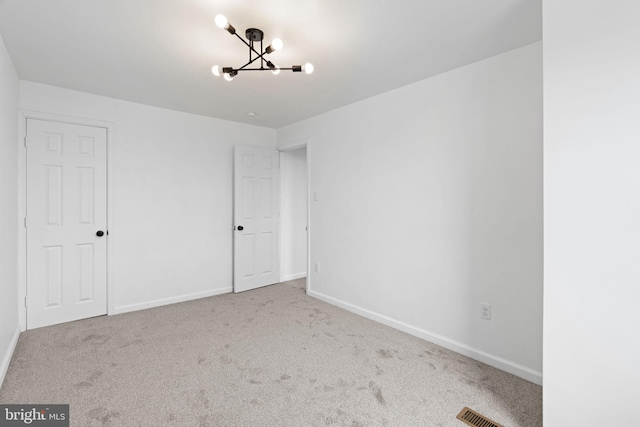 unfurnished bedroom with a chandelier, carpet, visible vents, and baseboards