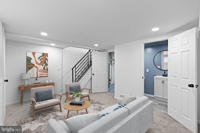 living area with recessed lighting, stairs, baseboards, and light colored carpet