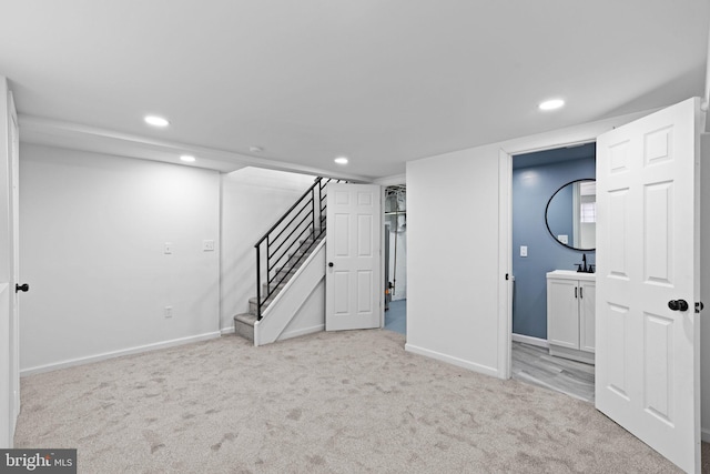 finished basement with light colored carpet, baseboards, recessed lighting, and stairs