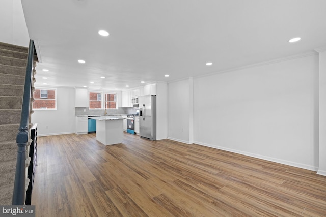 unfurnished living room featuring wood finished floors, recessed lighting, baseboards, and stairs
